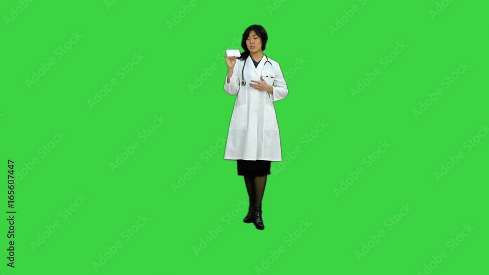 Attractive female doctor in lab coat with stethoscope talking with cellphone on a Green Screen, Chroma Key Attractive female doctor in lab coat with stethoscope talking with cellphone on a Green Screen, Chroma Key