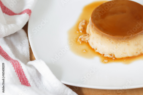 Konstfotografi Creme caramel in a white dish and with a cotton napkin.