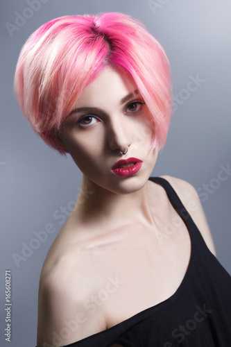 Beauty portrait of a sexy girl with pink hair on a gray background.