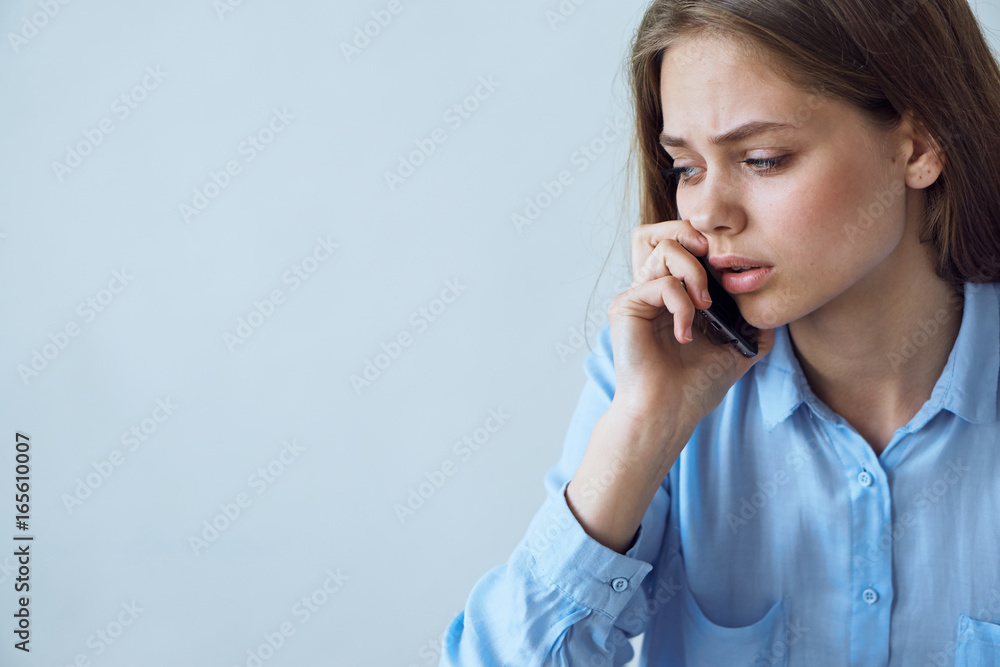 Beautiful young woman on a light background calls by phone Beautiful young woman on a light background calls by phone