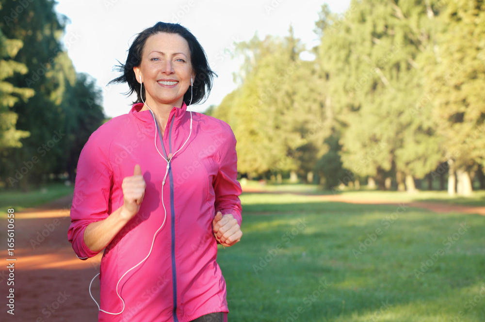 Portrait of elderly woman running with headphones in the park Portrait of elderly woman running with headphones in the park