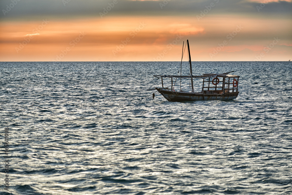 landestypische Dau schaukelt im Meer bei Sonnenuntergang, Sansibar, Tansania, Afrika 