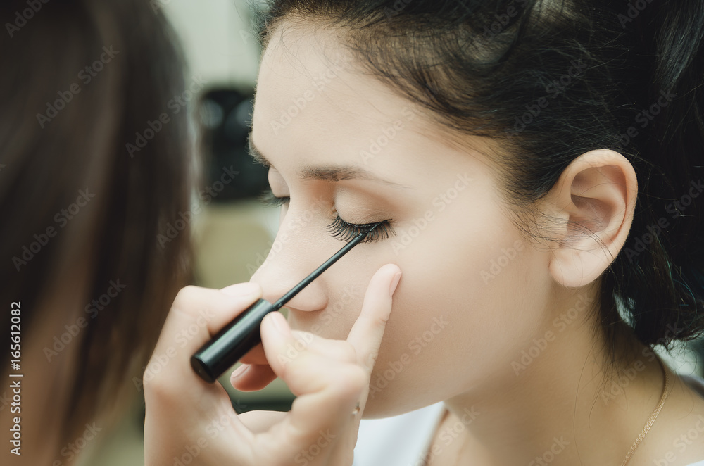 The make-up master paints the eyes of the girl. Makes makeup, close-up. The make-up master paints the eyes of the girl. Makes makeup, close-up.