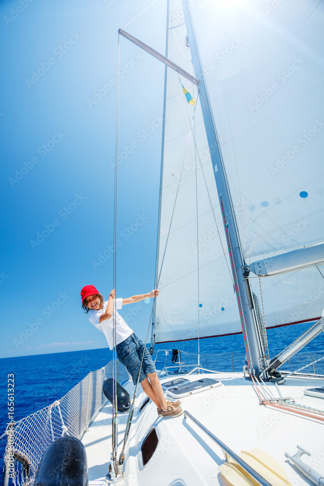 Fototapeta premium Little boy on board of sailing yacht on summer cruise. Travel adventure, yachting with child on family vacation.
