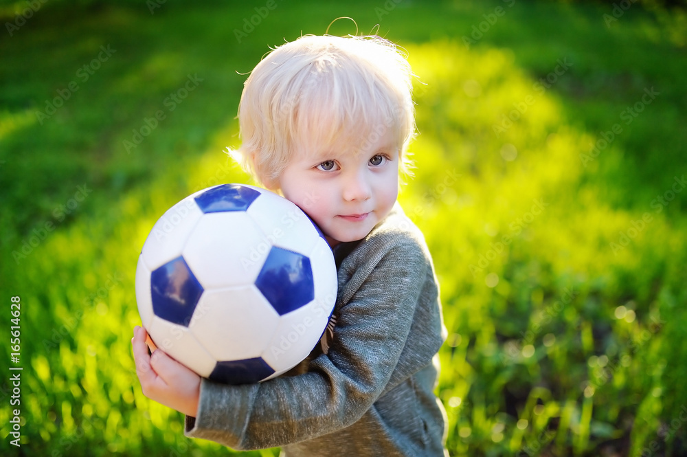 Little boy having fun playing a soccer game on sunny summer day Little boy having fun playing a soccer game on sunny summer day