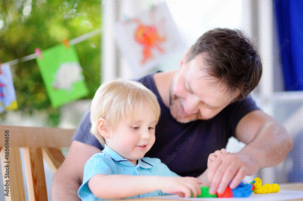 Little boy with his father playing with colorful modeling clay Little boy with his father playing with colorful modeling clay