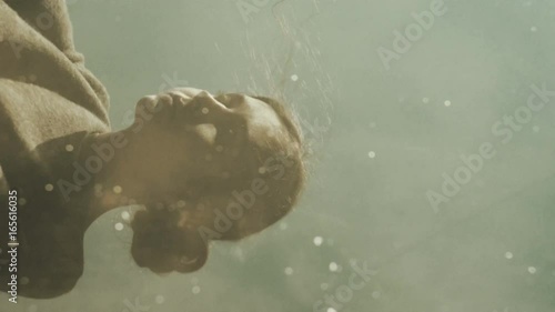 Tranquil scene of early morning lake with reflection of female face. Young woman looking into the water. Moody weather outdoors hangout.