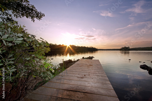 wooden pier at sunset by lake 