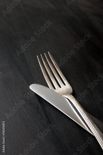 vintage silver knife and fork on dark background, vertical image