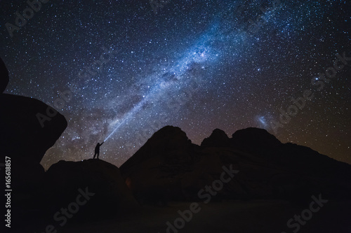 Landscape with Milky Way. Night sky with stars and silhouette of a standing man on the mountain.