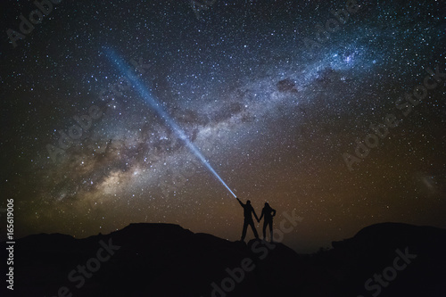 Landscape with Milky Way. Night sky with stars and silhouette of a couple on the mountain.
