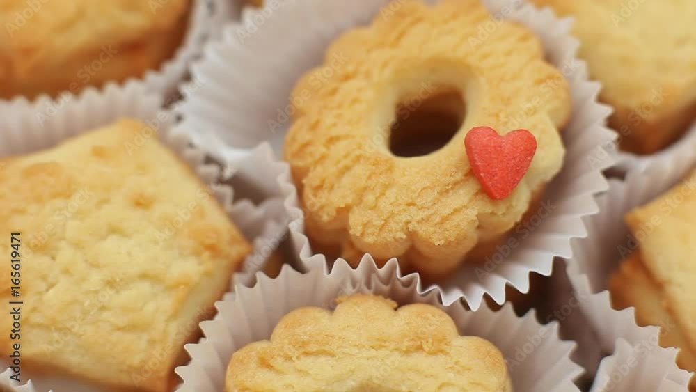 Baker sprinkling sugar powder over butter cookies Baker sprinkling sugar powder over butter cookies