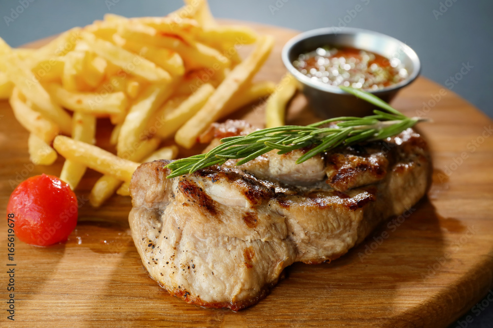 Delicious grilled steak and french fries on wooden board