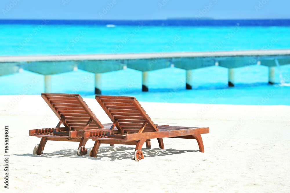 Fototapeta premium Wooden sun loungers on sea beach in summer day