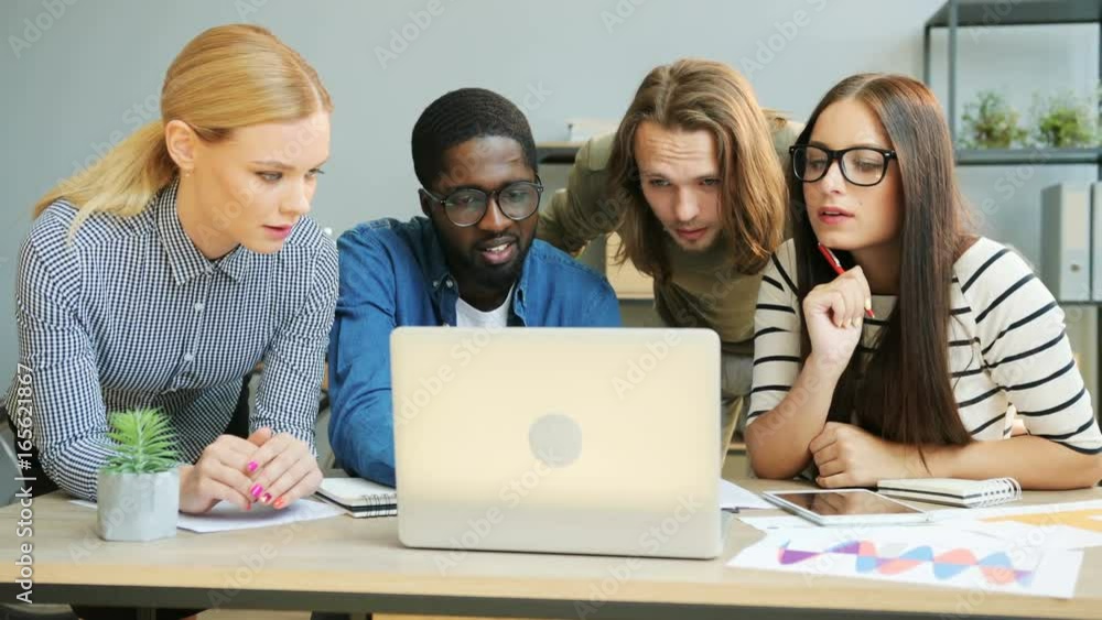 Multi ethnic business team, caucasian business man and women, african man work on creating a promising startup on the laptop. Multi ethnic business team, caucasian business man and women, african man work on creating a promising startup on the laptop.