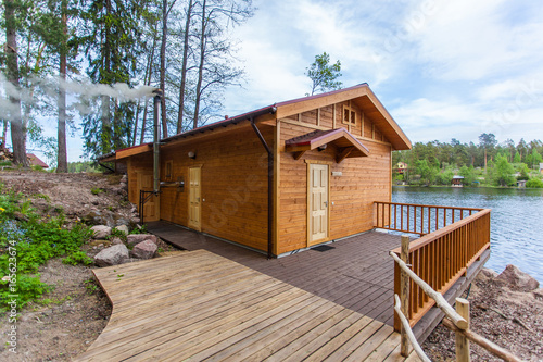 Smoke from the chimney of a wooden bath on the shore of the lake 