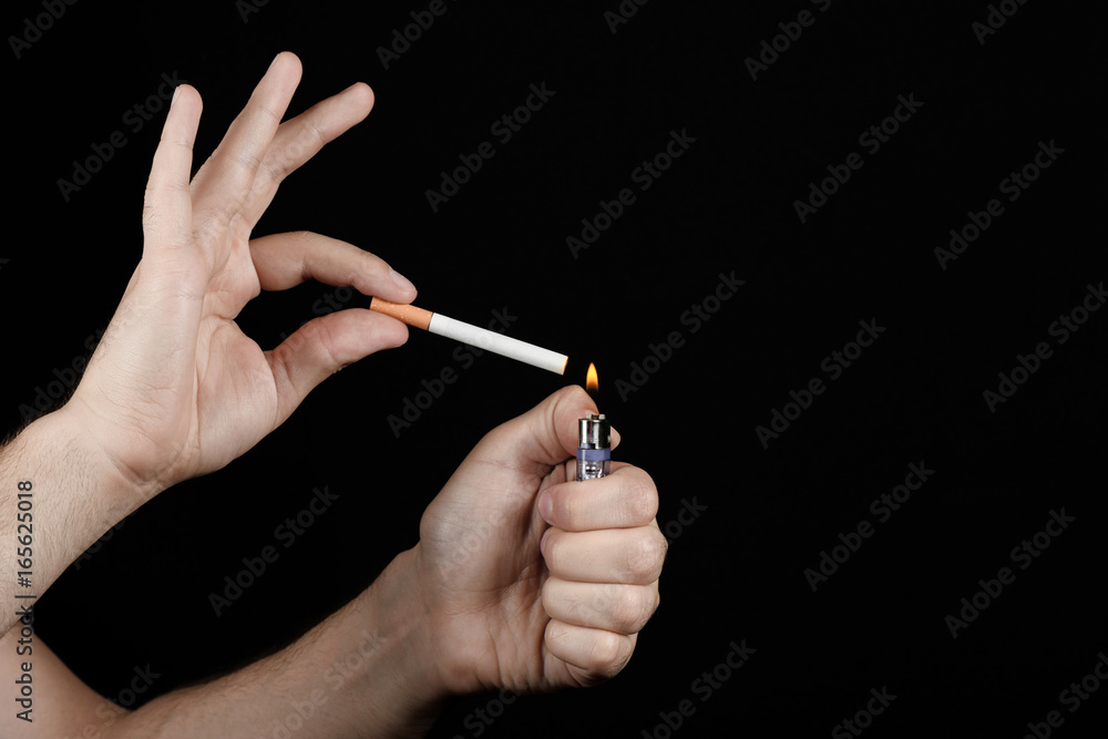Closeup of male hands holding a cigarette and a lighter ready to light it her fire. Studio photography. Unhealthy habits. Closeup of male hands holding a cigarette and a lighter ready to light it her fire. Studio photography. Unhealthy habits.