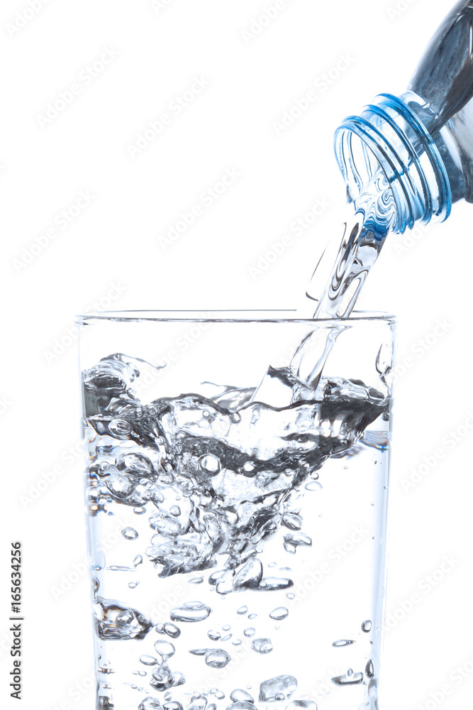 Pouring drinking water from bottle into glass on white background.