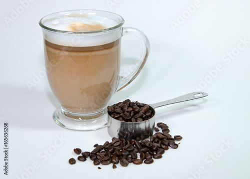 Latte in clear glass with coffee beans and scoop