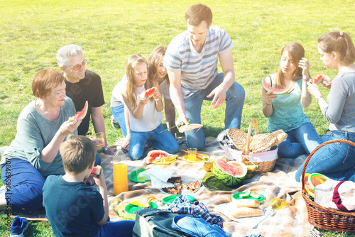 People of different ages sitting and talking on picnic