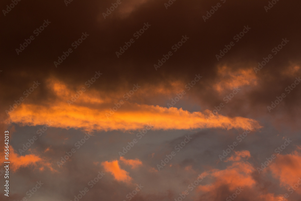 Sunset cloudscape - clouds making abstract shapes in the sky under sunset sunlight