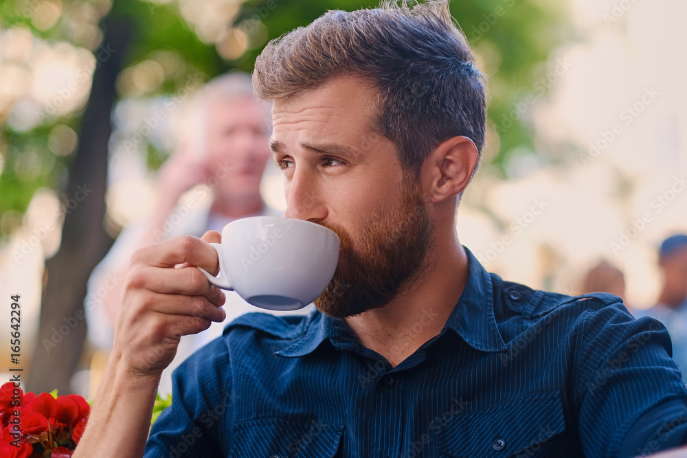 A man drinks coffee in a cafe on a street. A man drinks coffee in a cafe on a street.