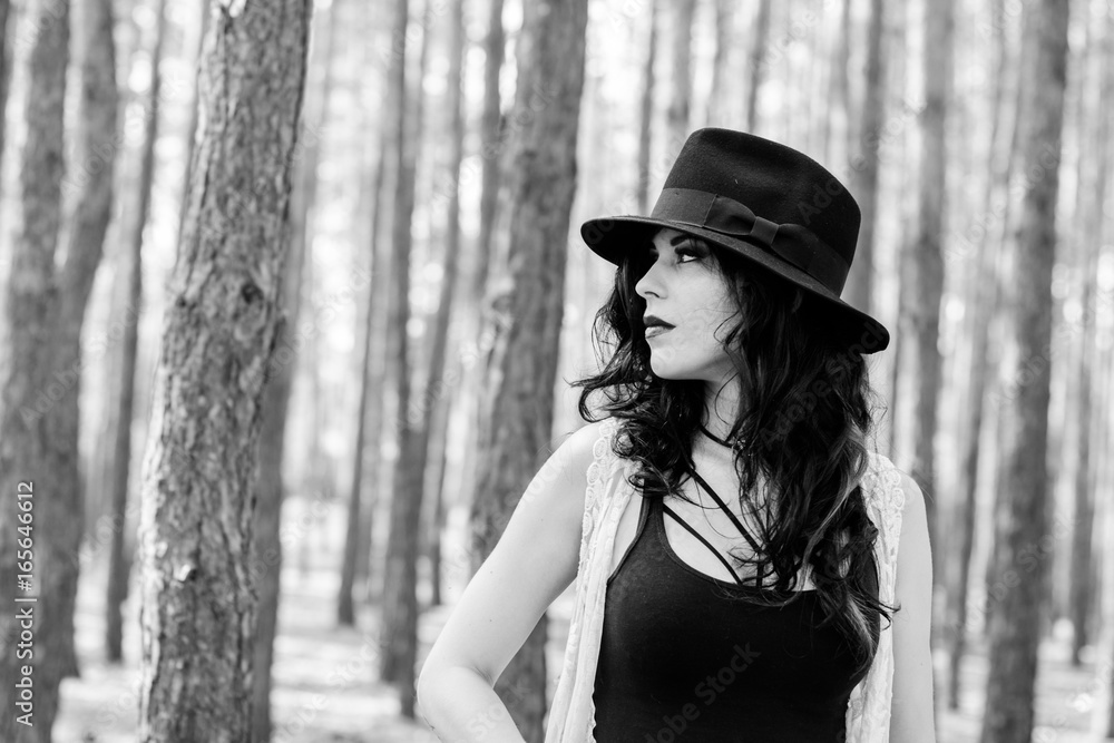 Gorgeous beautiful curly brunette woman with black hat and lace cardigan, in boho style walk in forest and thinkin about life, near wood Gorgeous beautiful curly brunette woman with black hat and lace cardigan, in boho style walk in forest and thinkin about life, near wood