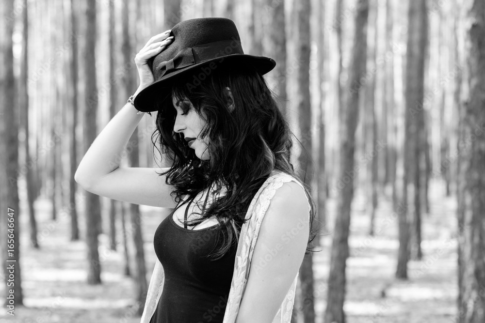 Gorgeous beautiful curly brunette woman with black hat and lace cardigan, in boho style walk in forest and thinkin about life, near wood Gorgeous beautiful curly brunette woman with black hat and lace cardigan, in boho style walk in forest and thinkin about life, near wood