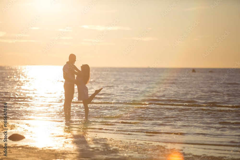 A young couple in love, on the shore of the Bay at sunset