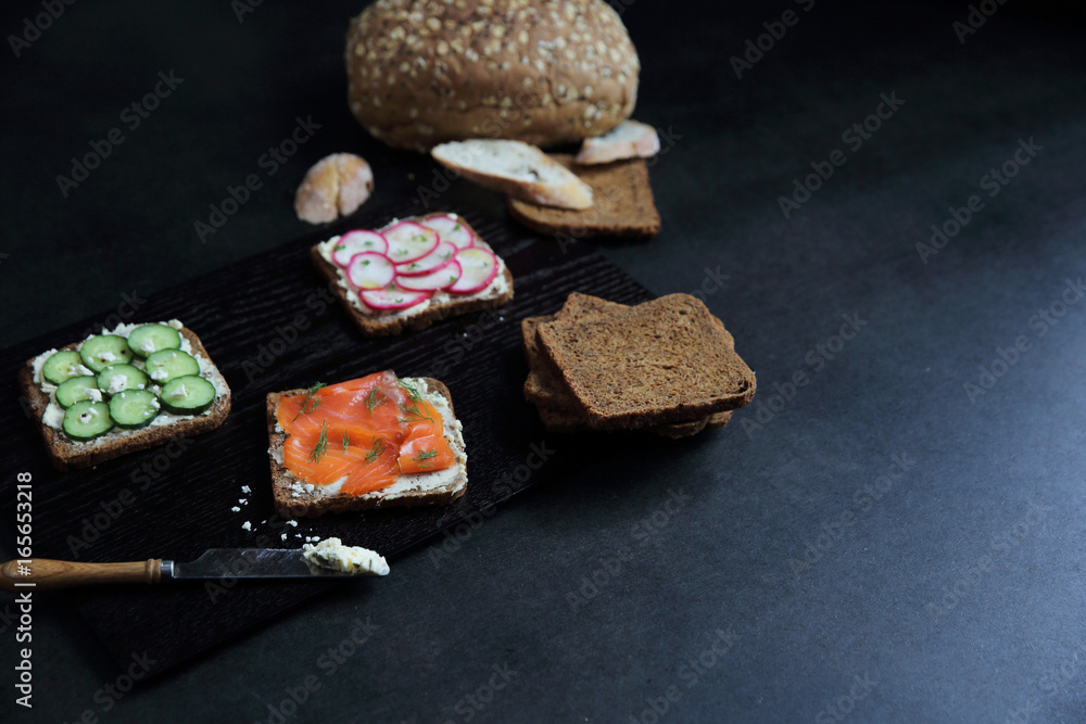 Sandwich with cereals bread smoked salmon beetroot and cucumber on dark marble background
