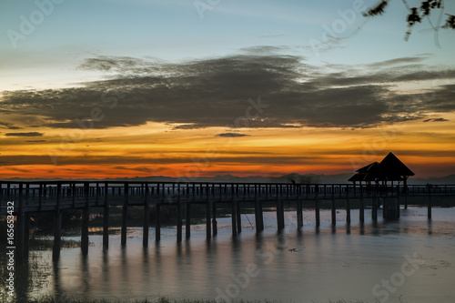 A beautiful twilight on a wooden bridge stretching to the lake   © apichai507