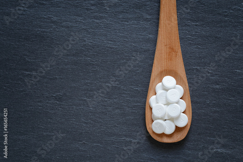 Supplement pills on wooden spoon