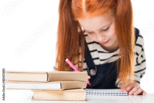 close-up view of books on desk and schoolgirl drawing with felt tip pen isolated on white