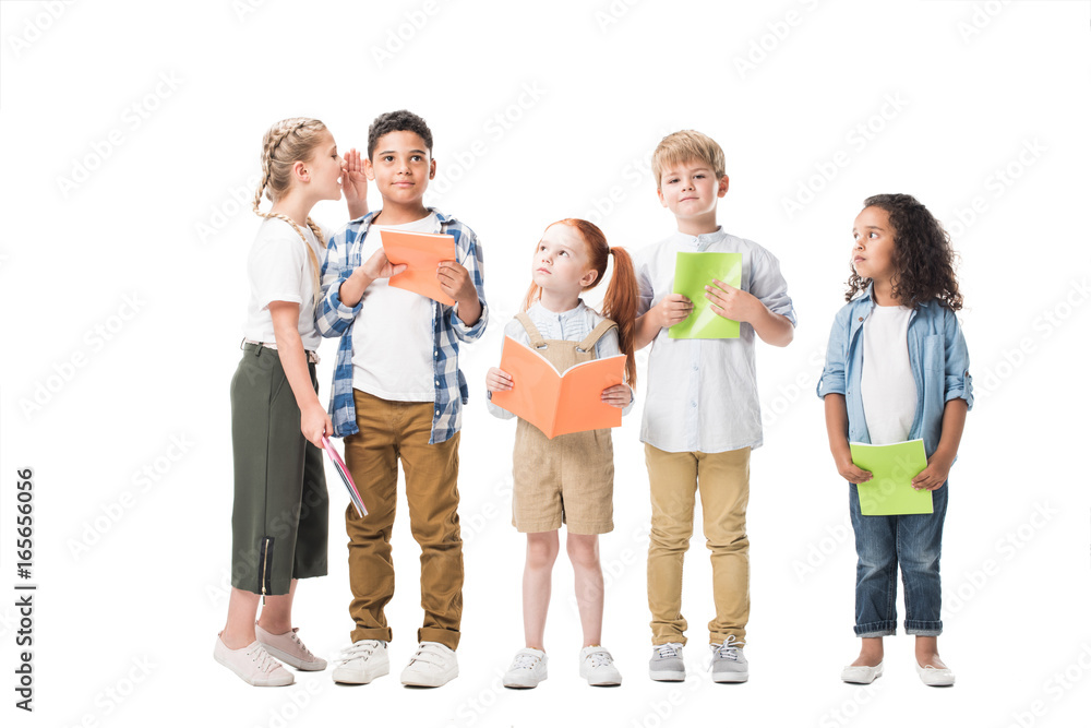 happy multiethnic children holding textbooks and standing together isolated on white