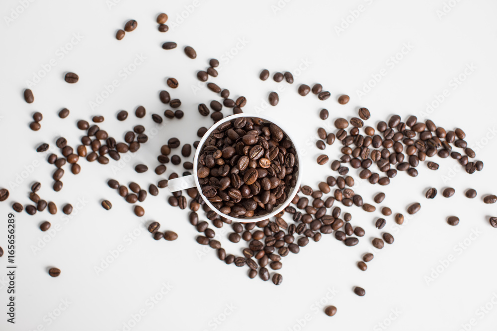 top view of white cup with scattered coffee beans, isolated on white top view of white cup with scattered coffee beans, isolated on white