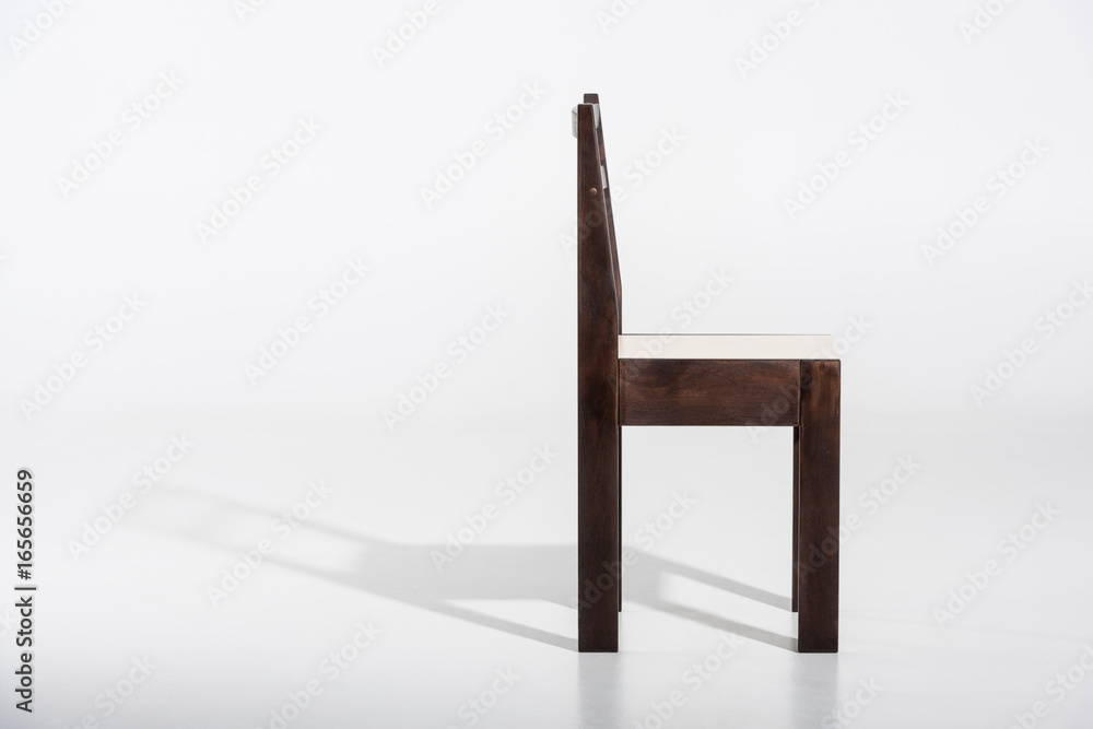 Classic dark wooden chair with white top standing on white floor in studio Classic dark wooden chair with white top standing on white floor in studio