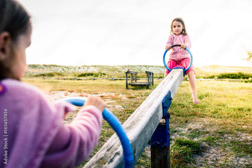 Ταπετσαρία Little twin girls children are riding seesaw swing in park.