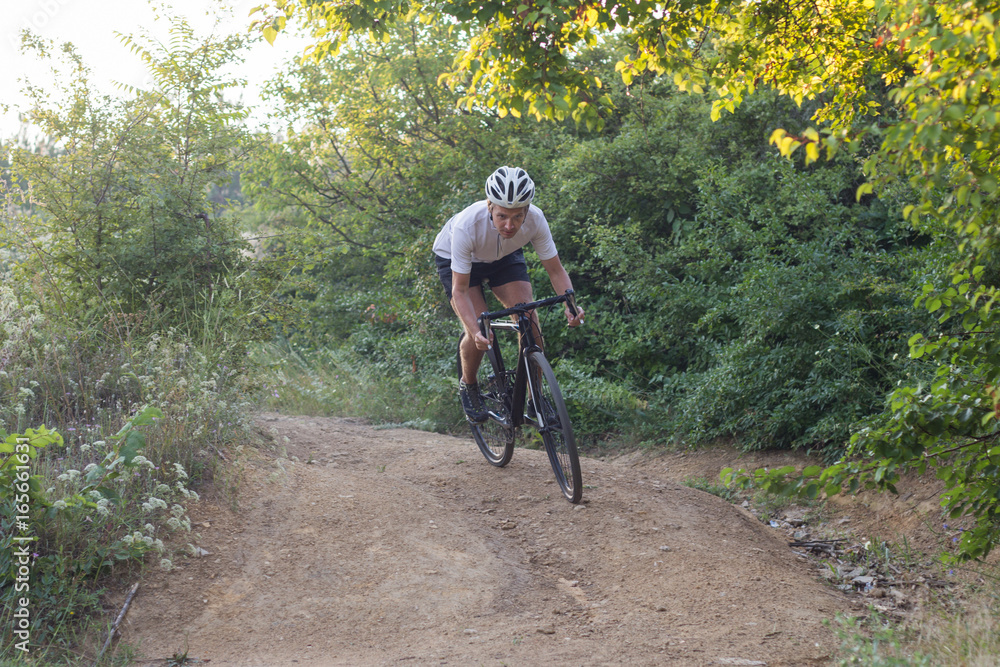 Male in helmet and sportswear on his cyclocross bike, riding on the country roads 