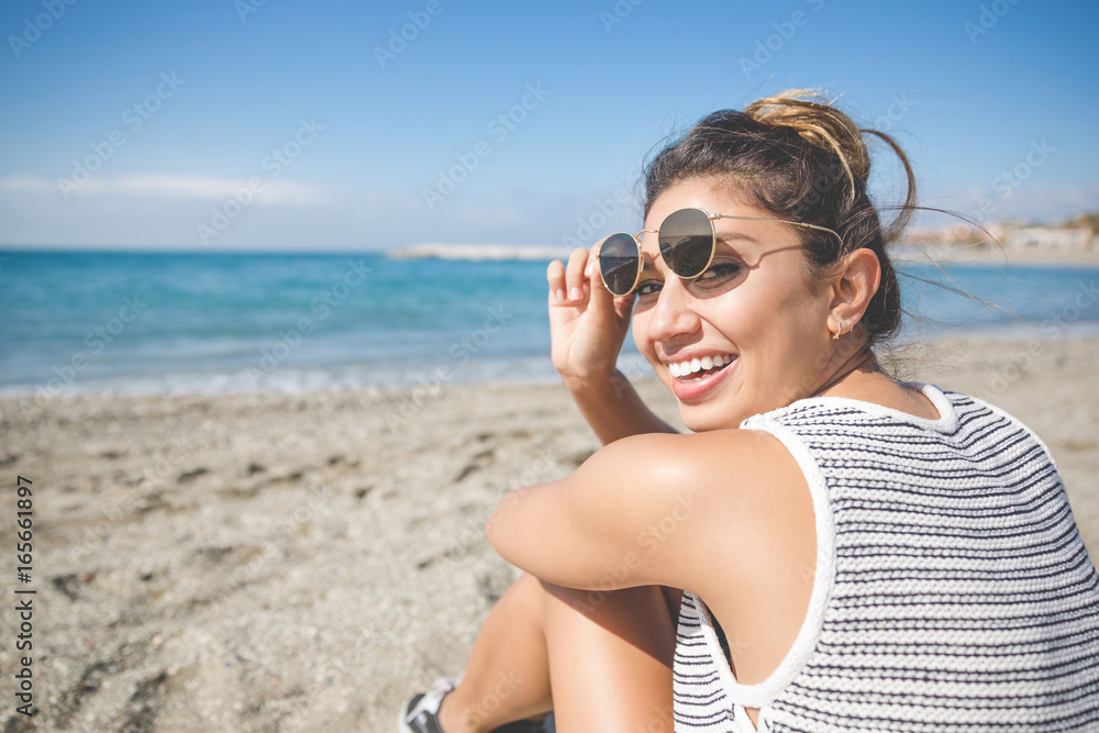 Pretty young woman sitting on beach laughing Pretty young woman sitting on beach laughing