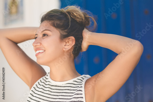 Young happy woman holding hands above head looking away