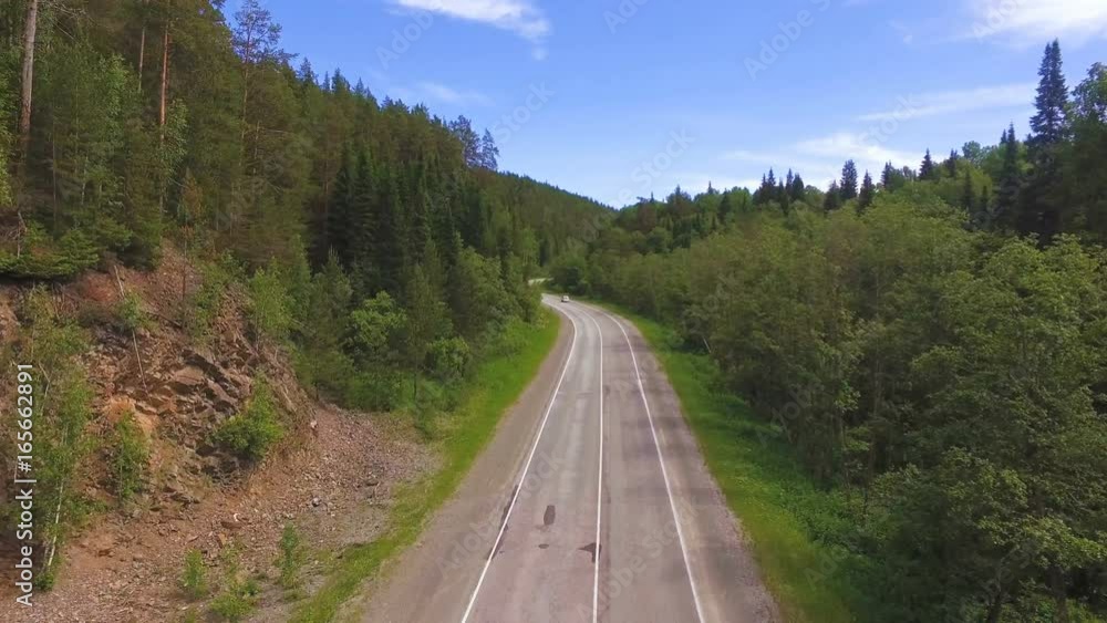 AERIAL: Flying above the forest to the mountain road with cars. People traveling, road trip through beautiful mountain scenery in sunny summer AERIAL: Flying above the forest to the mountain road with cars. People traveling, road trip through beautiful mountain scenery in sunny summer