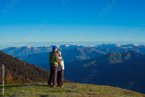 Couple of travelers, hugging, is admiring the dawn in the mountains © sanechka