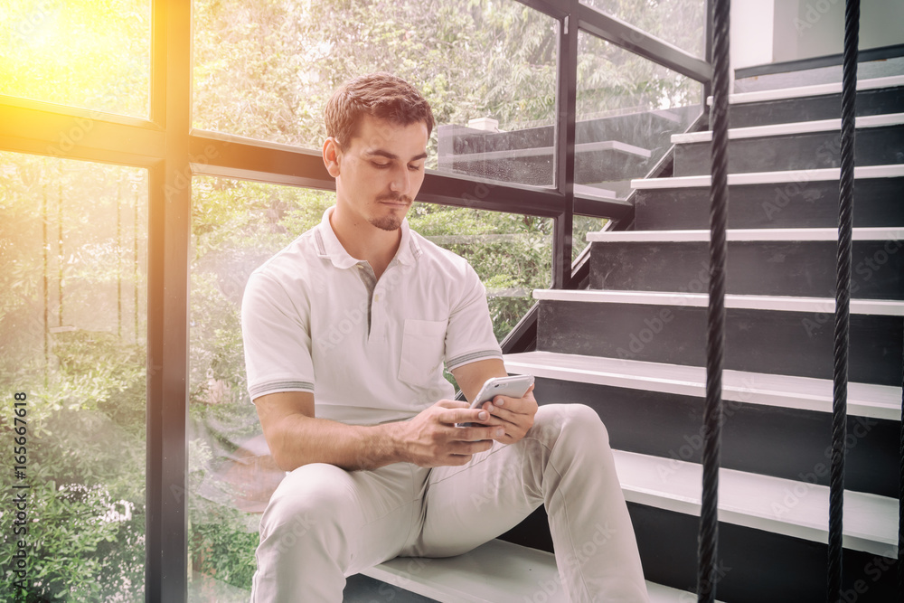 young man sitting on stair and using mobile phone young man sitting on stair and using mobile phone