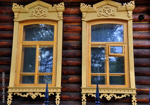 Drei kunstvoll geschnitzten Fenster an der Fassade eines alten Holzhauses photo