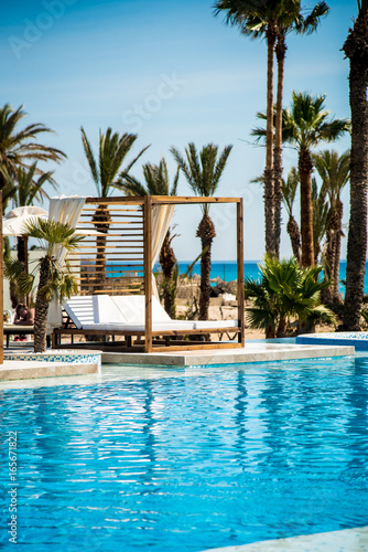 Luxury Sofa Bed with Soft Pillow as Interior Furniture with Blue Pool and Palm Trees