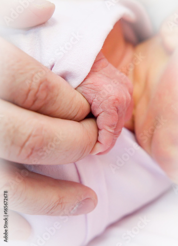 Newborn baby holding parents fingers.