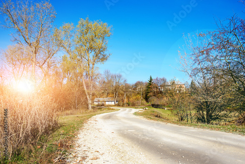 An autumn winding rural country road to the old hut located amid trees landing