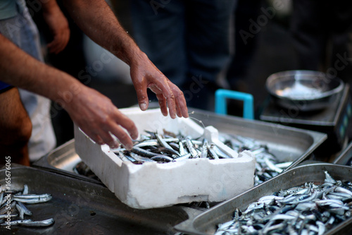 The seller in the fish market puts on the counter fresh anchovies