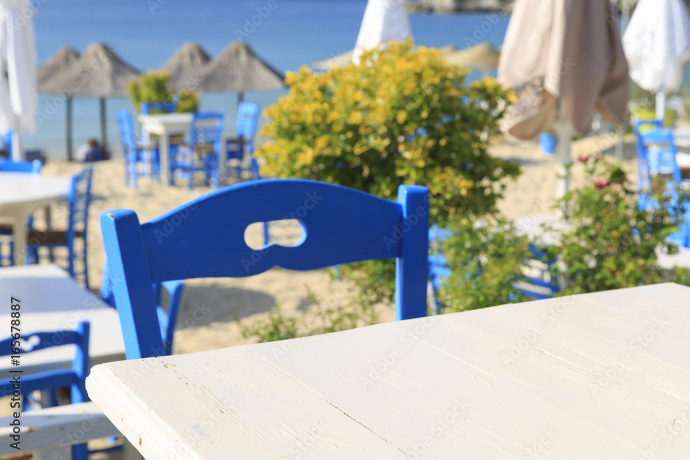 White wooden picnic table by the sea in Greece, Empty picnic table for product display, Defocused beach in the background