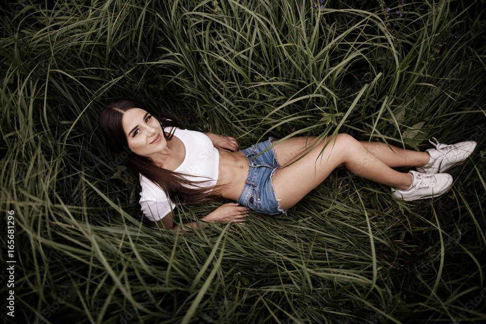 Full-length beautiful woman on the grass. Woman relaxing outdoors looking happy and smiling. Full-length beautiful woman on the grass. Woman relaxing outdoors looking happy and smiling.